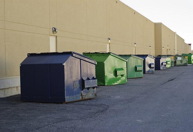 a construction worker disposing of debris into a dumpster in Atkins